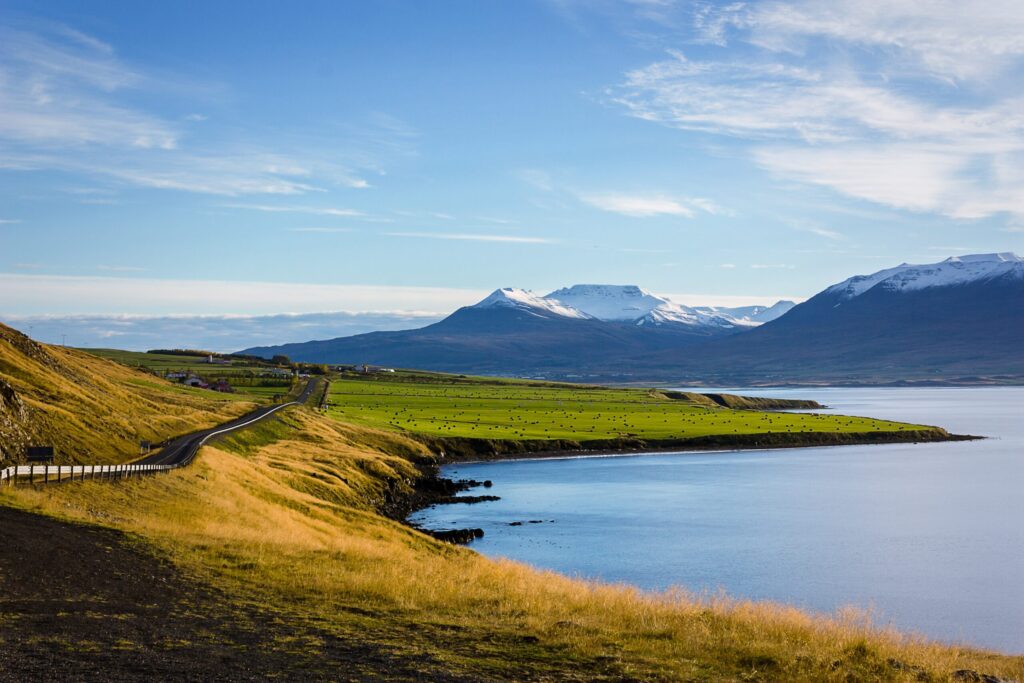 field and mountain near body of water while enjoying the best time to visit in Iceland